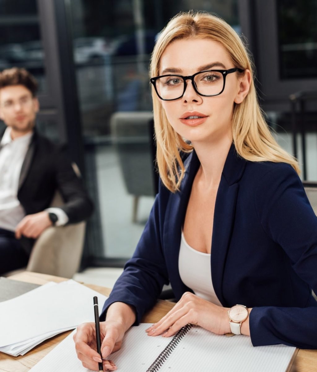 selective focus of businessman looking at businesswoman in eyeglasses that looking at camera at